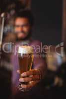 Male bar tender holding glass of beer