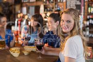 Portrait of beautiful woman holding drink while sitting with friends