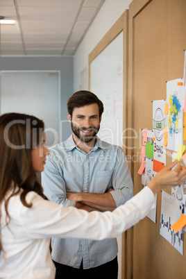 Smiling businessman with female colleague analyzing charts at office