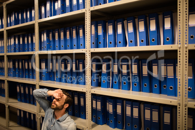 Tired businessman sitting in file storage room