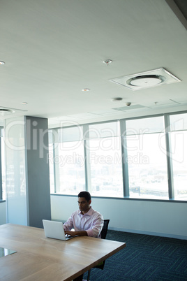 Businessman typing on laptop in conference room