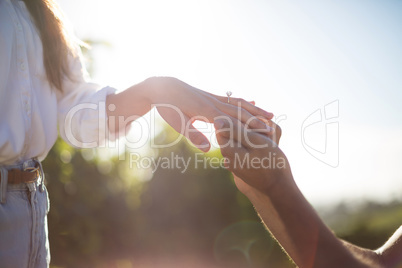 Hands of man putting ring on girlfriend finger