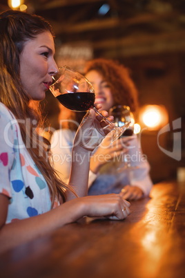 Two young women having red wine in pub
