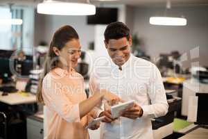 Happy colleagues discussing over digital tablet