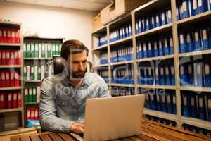 Businessman using laptop in file storage room