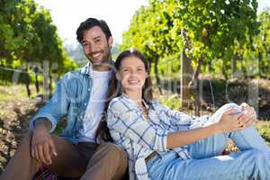 Portrait of happy couple sitting at vineyard