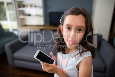 Girl sticking out tongue while holding mobile phone