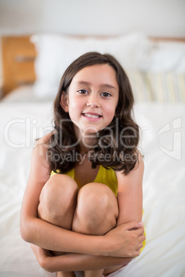 Portrait of smiling girl sitting on bed