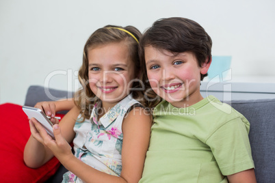 Sibling sitting on sofa with mobile phone in living room