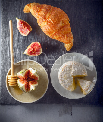 Croissant with soft cheese and figs on a stone plate