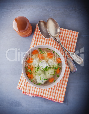 Chicken soup with meatballs and vegetables with a napkin.