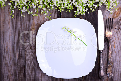 White plate with vintage iron cutlery on a gray wooden surface