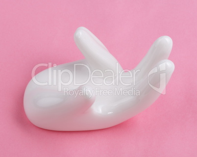 Ceramic stand with hand shape on pink background