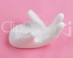 Ceramic stand with hand shape on pink background