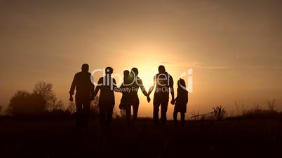 Three generation family walk in meadow at sunset