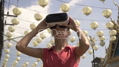 Woman uses virtual reality glasses outdoors