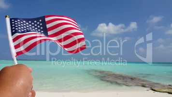 v01147 Maldives beautiful beach background white sandy tropical paradise island with blue sky sea water ocean 4k hand holding us american flag