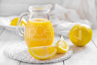 Lemon juice in glass jug and fresh fruits on white wooden background, vitamin drink or cocktail