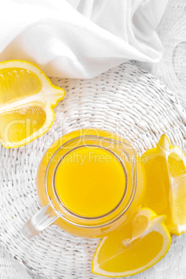 Lemon juice in glass jug and fresh fruits on white wooden background, vitamin drink or cocktail