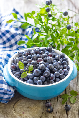 Fresh blueberries with leaves on wooden background