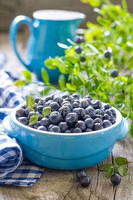 Fresh blueberries with leaves on wooden background