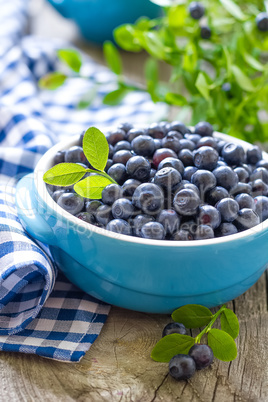 Fresh blueberries with leaves on wooden background