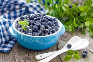 Fresh blueberries with leaves on wooden background