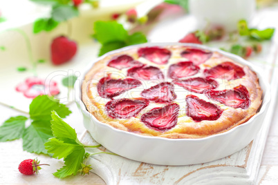 Delicious strawberry tart or cheesecake with fresh berries and cream cheese, closeup on white wooden rustic background