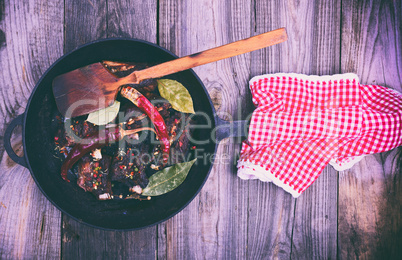 Cooked pork ribs on a black cast-iron frying pan with a handle