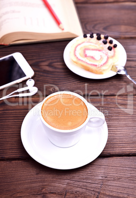 cup of coffee and a mobile phone on a brown table