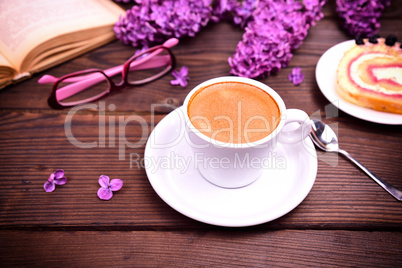 Espresso in a white cup with a saucer on a brown table