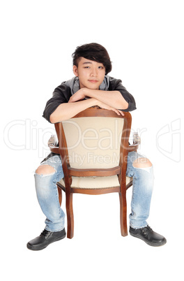 Asian man sitting backwards on chair.