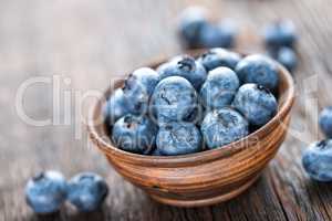 Fresh Blueberry in bowl on wooden background, closeup