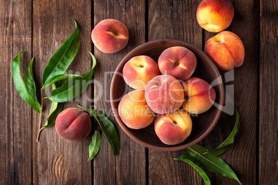 Fresh juicy peaches with leaves on dark wooden rustic background