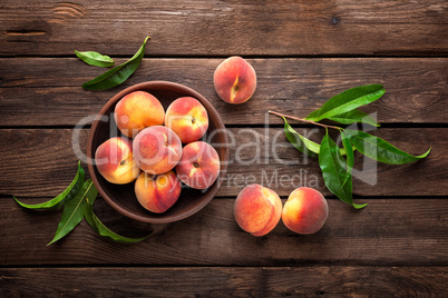 Fresh juicy peaches with leaves on dark wooden rustic background