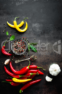 Red hot chili pepeprs and peppercorns on black metal background, top view