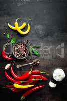 Red hot chili pepeprs and peppercorns on black metal background, top view