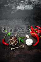 Red hot chili pepeprs and peppercorns on black metal background, top view