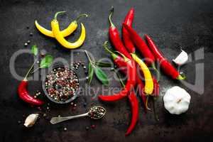 Red hot chili pepeprs and peppercorns on black metal background, top view