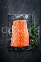 Raw salmon filet on dark slate background, wild atlantic fish