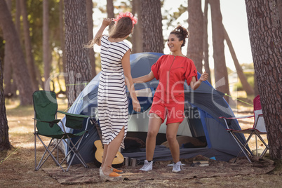 Cheerful female friends enjoying together by tent