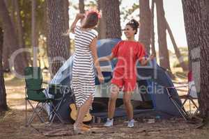 Cheerful female friends enjoying together by tent