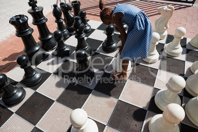 High angle view of girl bending by chess pieces