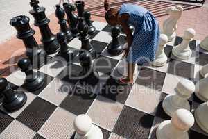 High angle view of girl bending by chess pieces