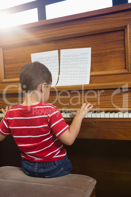 Rear view of cheerful friend playing piano while sitting in classroom