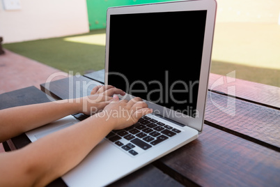 Close up of boy using digital laptop while sitting at table