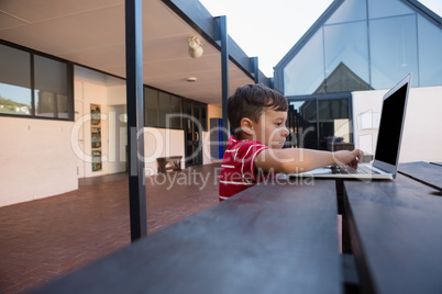 Side view of boy using digital laptop while sitting at table