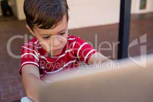 Close up of boy using laptop computer while sitting on chair