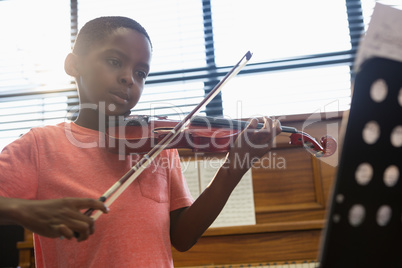 Boy playing violin while sitting in classroom
