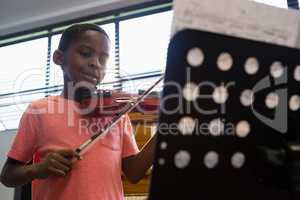 Smiling boy playing violin while standing in classroom